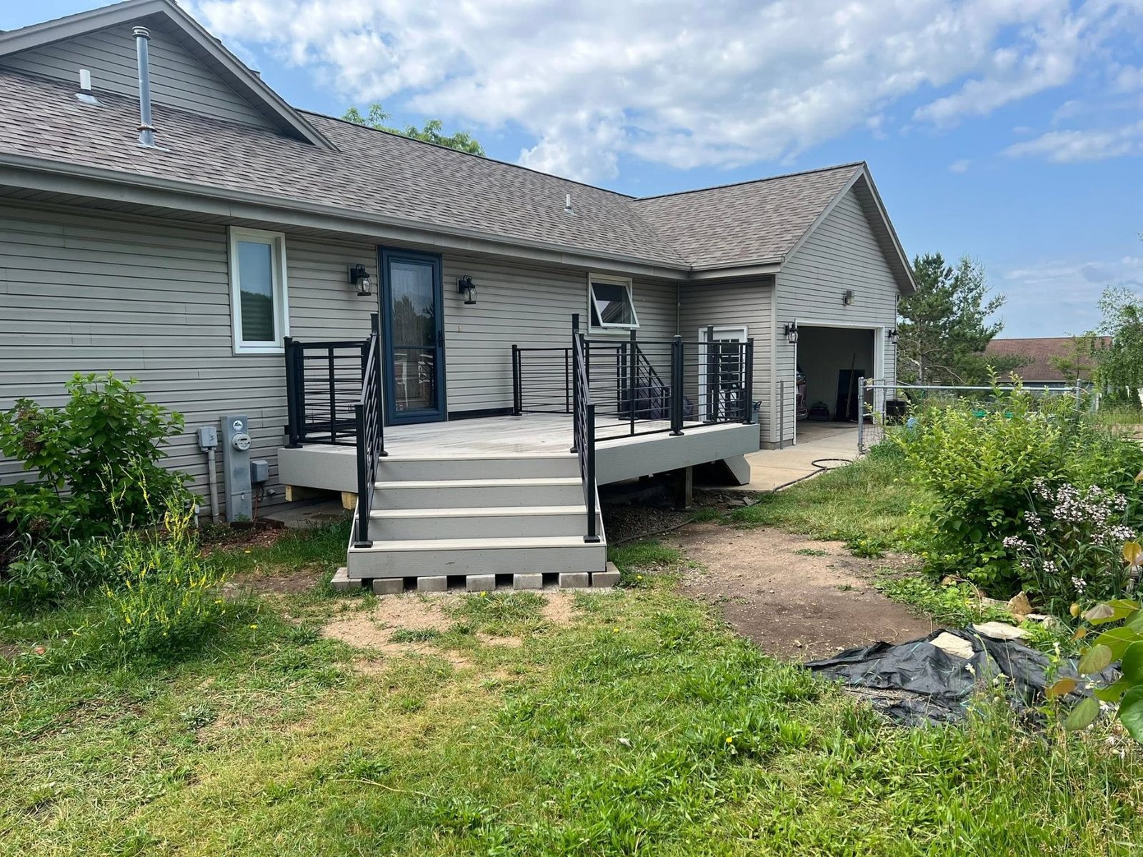 Composite deck with black metal railings on a gray ranch home
