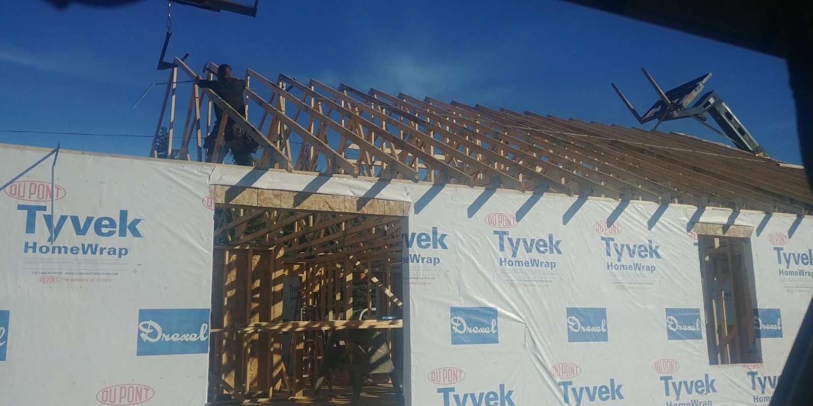 New home framed and wrapped, roof framing in progress